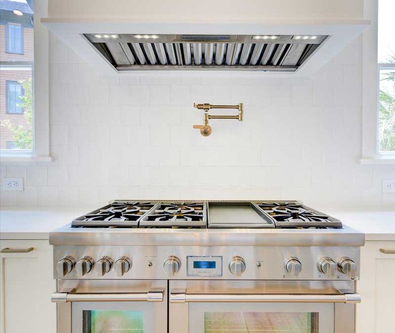 Professional stainless stove with in-wall faucet.